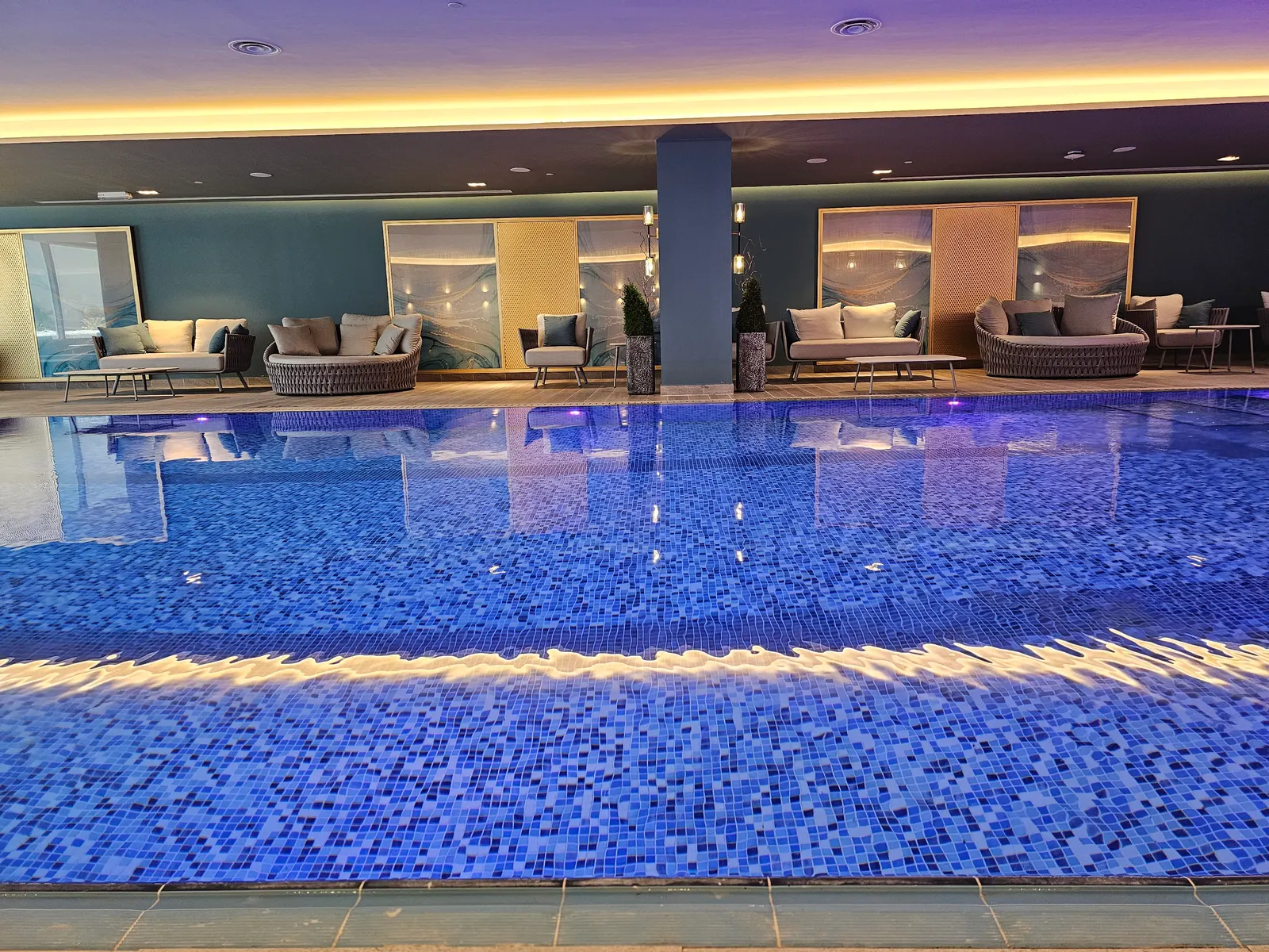 Indoor pool with loungers along the glass wall
